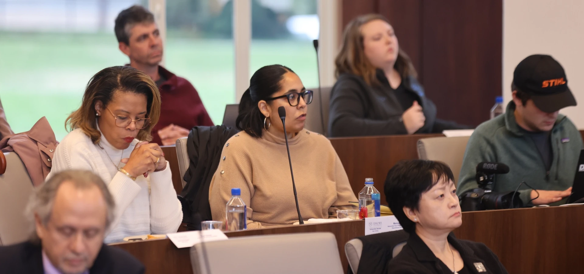 Emory University Senate members seated at desks with microphones listening attentively during a session