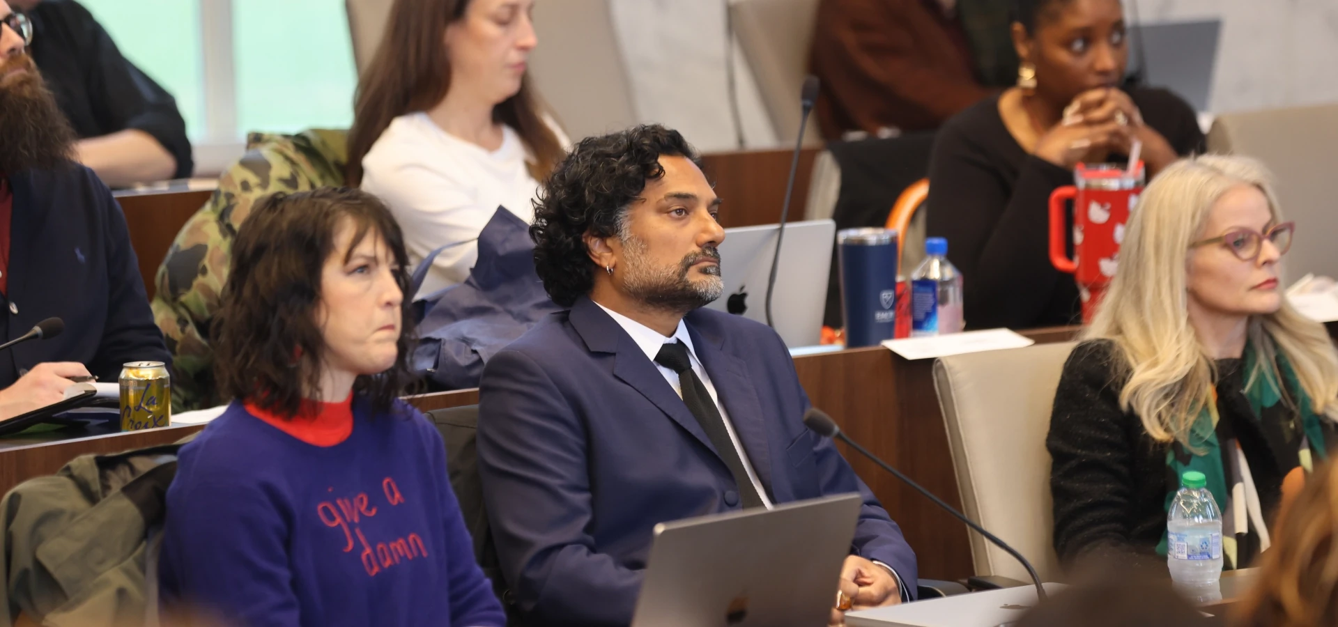 Emory University Senate members seated with laptops at tiered desks during an active session