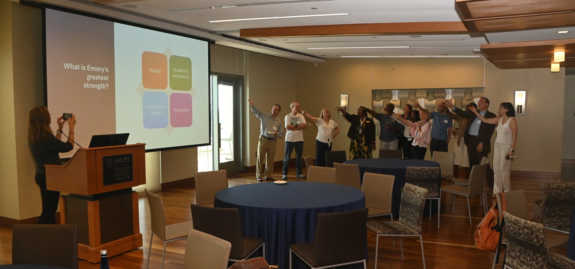 University Senate members participate in a group activity during a retreat, pointing toward a presentation screen displaying the question 'What is Emory's greatest strength?