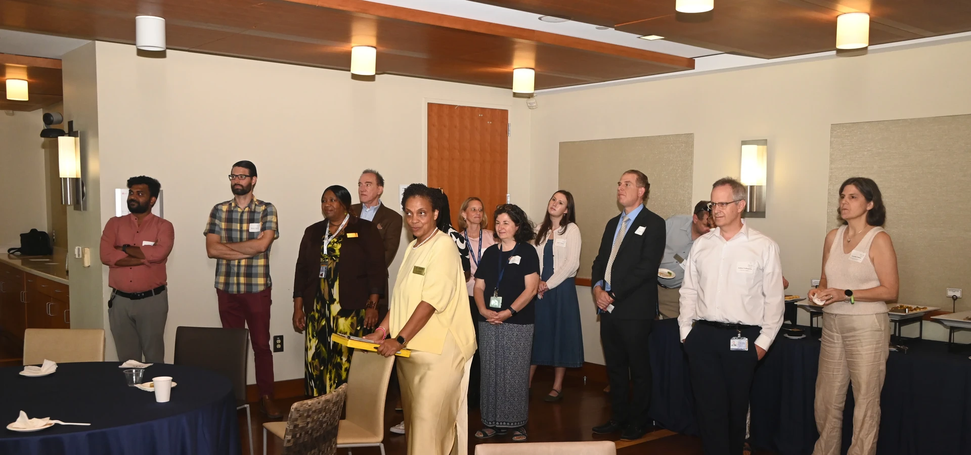University Senate members stand together during a retreat session, listening attentively to a presentation