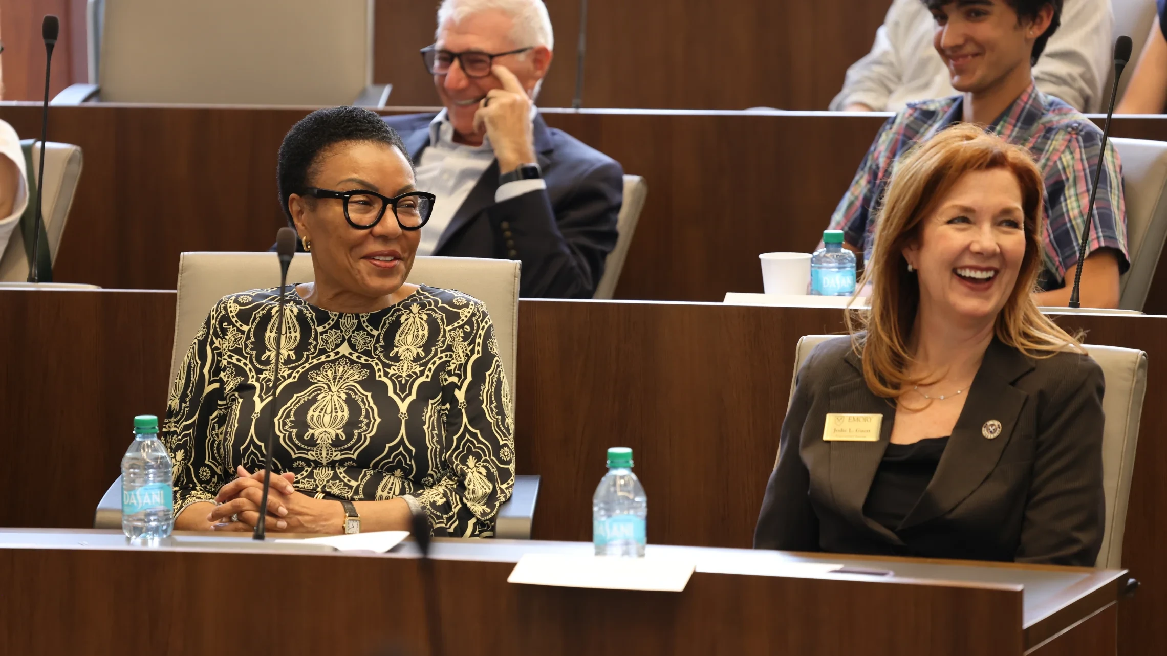 Attendees smile during a University Senate meeting in a lecture hall